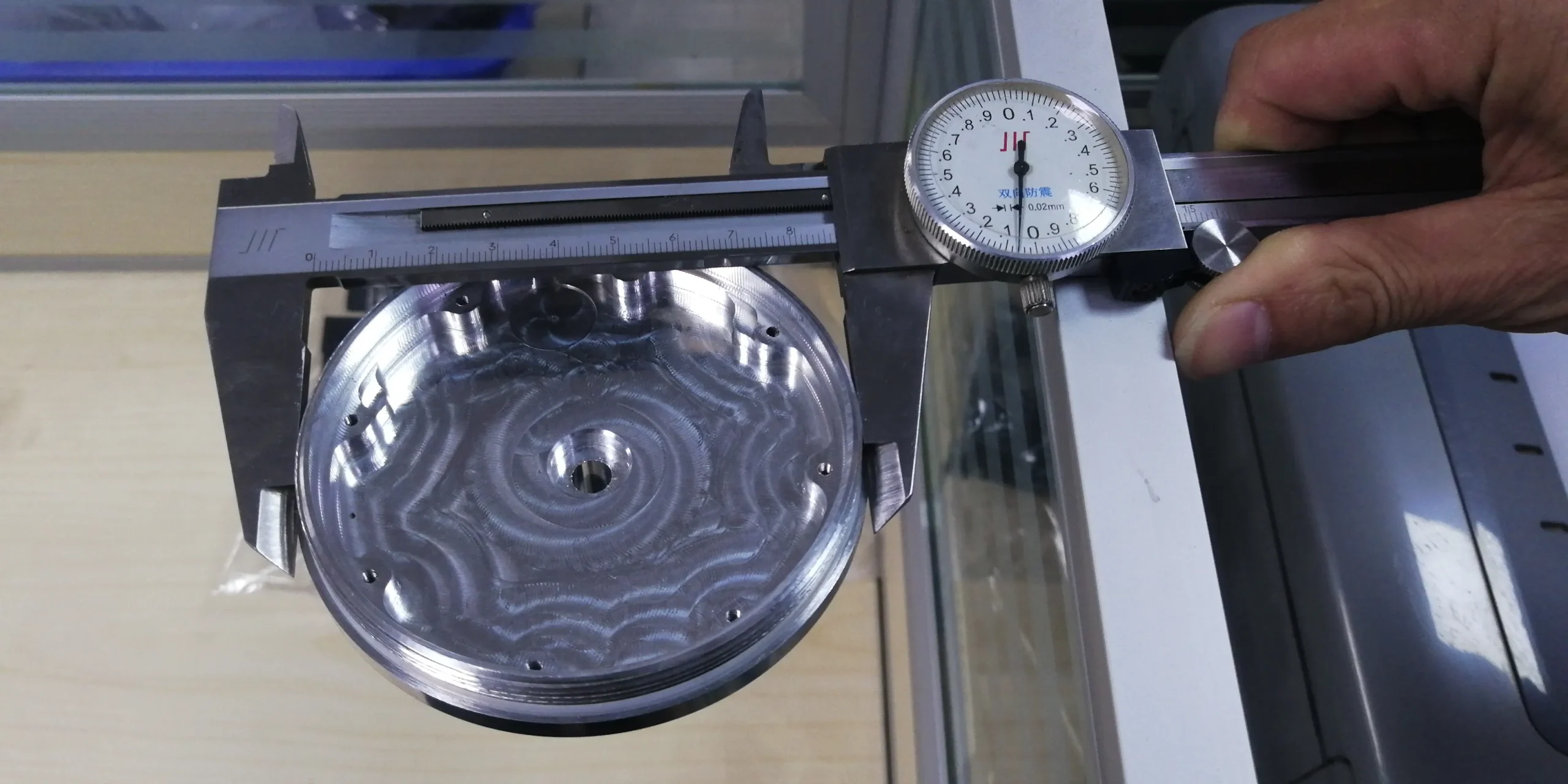 Dial caliper measuring the diameter of a precision CNC machined metal component
